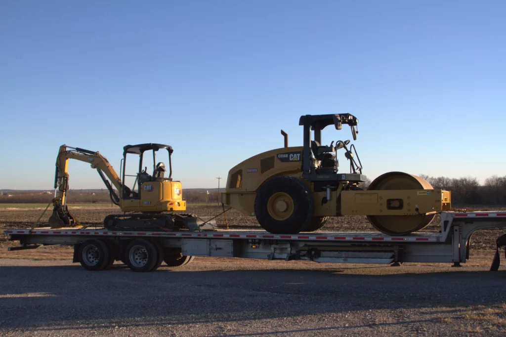 Heavy equipment rental trailer transporting an excavator and a road roller.