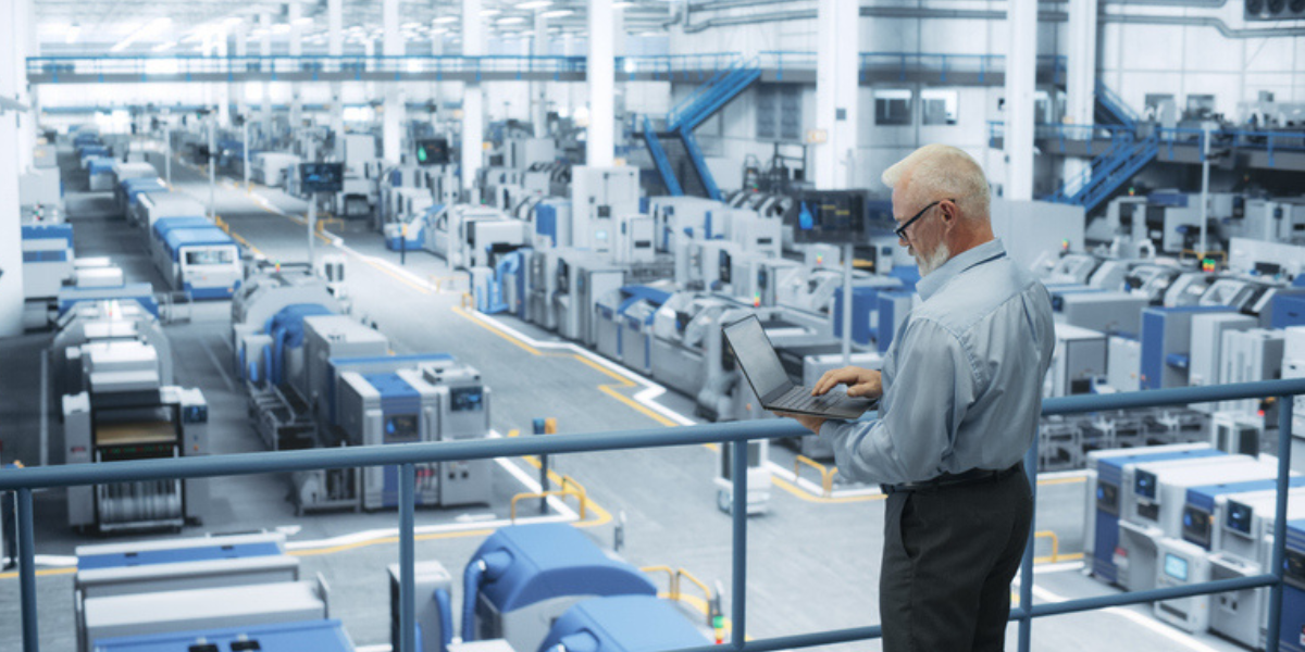 Industrial maintenance manager using laptop in a modern manufacturing facility